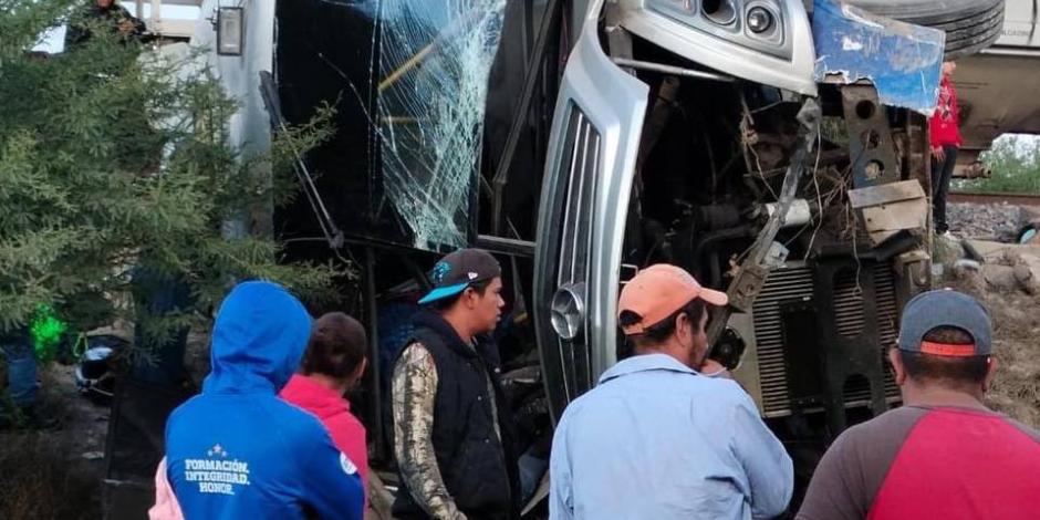 El autobús de pasajeros quedó volcado  tras ser impactado por un tren, ayer.