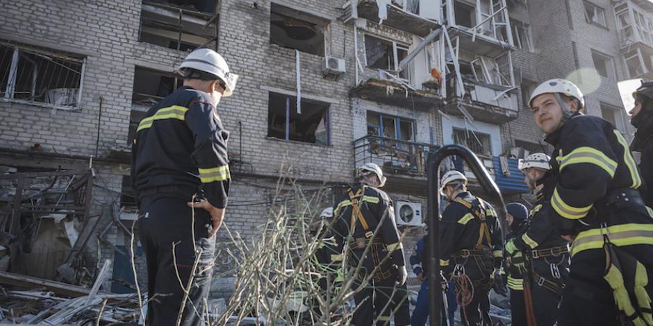 Personal de emergencias y bomberos se preparan para inspeccionar un edificio residencial impactado por un misil, ayer.