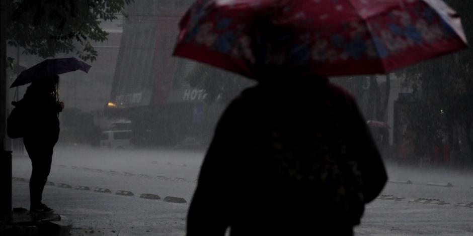Dos personas con paraguas caminan bajo la lluvia en la CDMX