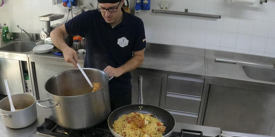 Un cocinero prepara pasta con cangrejo azul en un restaurante de Orbetello, Italia, el lunes 14 de agosto de 2023.