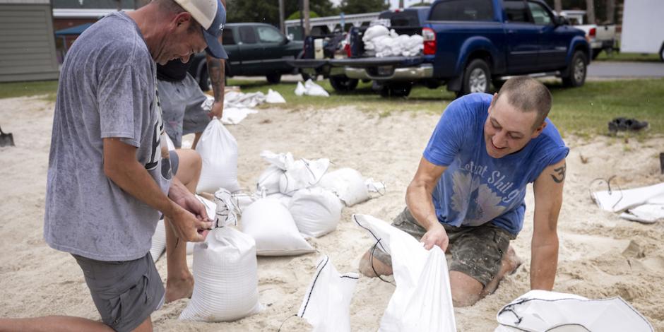 Residentes colocan costales de arena para anticiparse a los estragos por el huracán que alcanzó nivel 2, ayer.