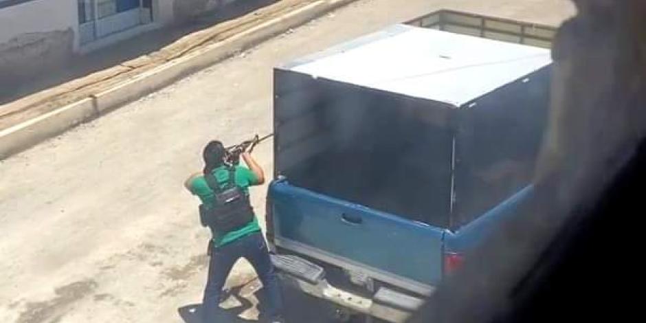 Un hombre armado se resguarda en un camión durante el enfrentamiento registrado el martes en Xoxtla.