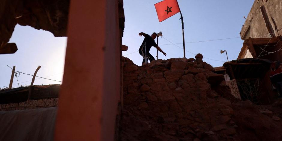 Un hombre camina entre los escombros, junto a una bandera marroquí, tras un terremoto mortal en el pueblo de Talat N'Yaaqoub, Marruecos.