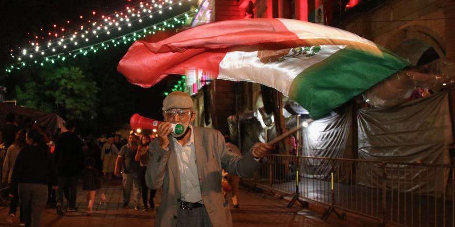 Un hombre ondea una bandera de México durante las fiestas patrias en Oaxaca.