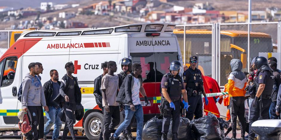 Policías vigilan a decenas de indocumentados en las Islas Canarias auxiliados por cuerpos de emergencias, el pasado 3 de octubre.