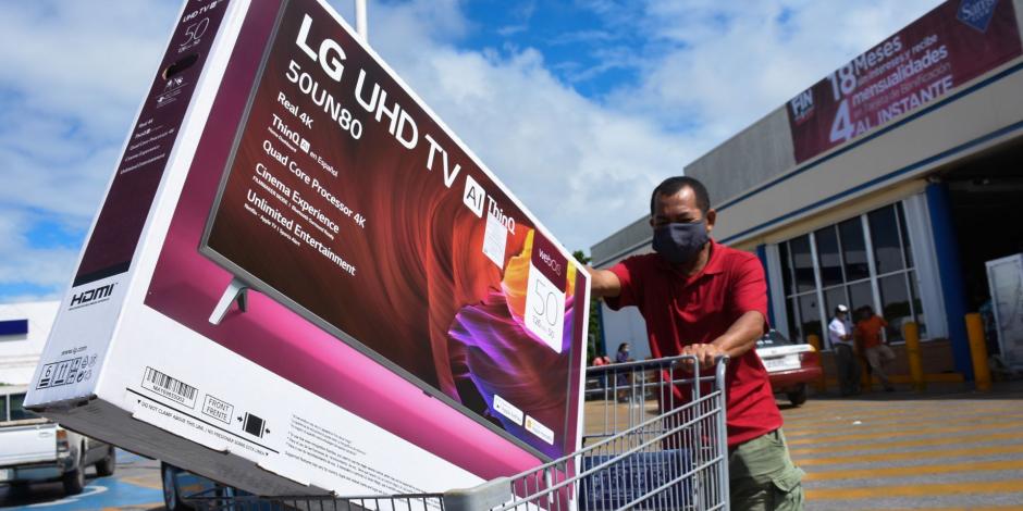 Un hombre empuja un carrito de supermercado en el que lleva una Smart TV que acaba de adquirir