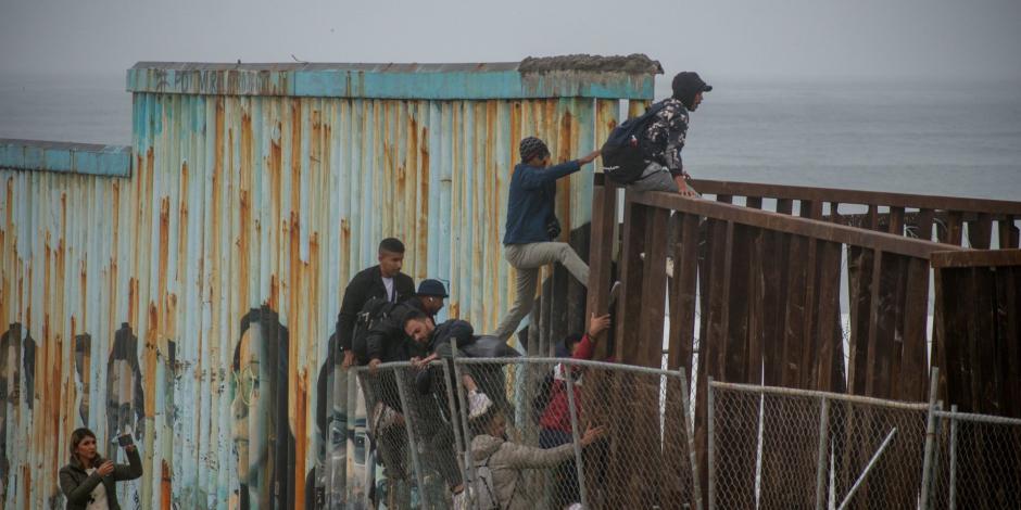 Migrantes intentan cruzar el muro fronterizo de Playas de Tijuana.