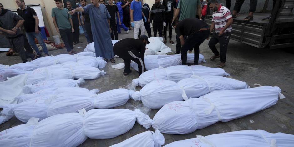 Residentes palestinos caminan entre decenas de cadáveres que saturan las morgues por nuevos bombardeos, ayer.