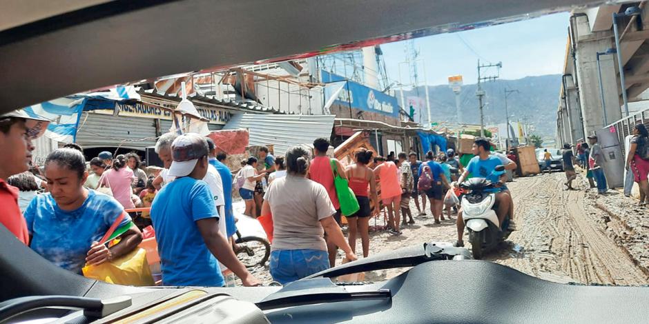 Personas obstruyen el paso sacando los muebles de tiendas, ayer, en Acapulco.