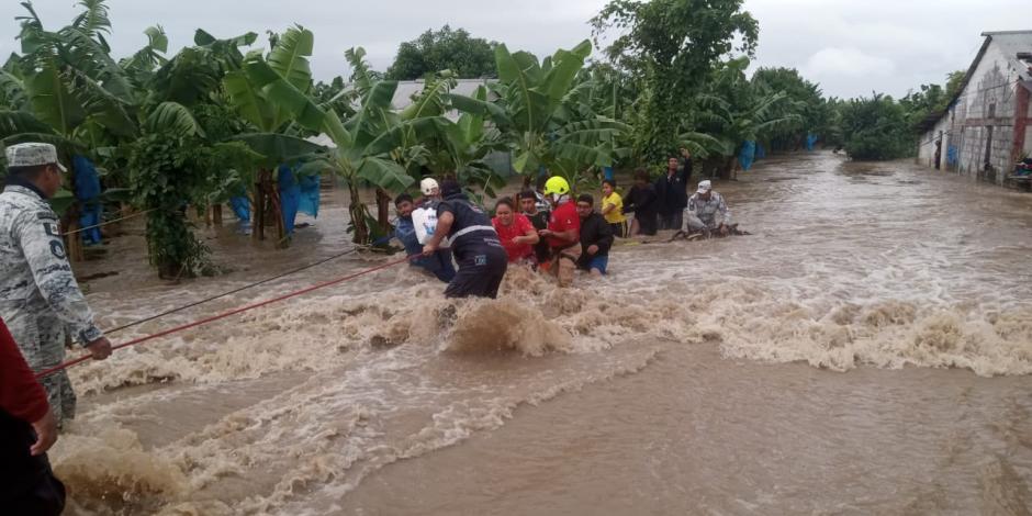 Elementos de la Guardia Nacional y de Protección Civil ayudan a pobladores a salir de La Providencia, ayer.