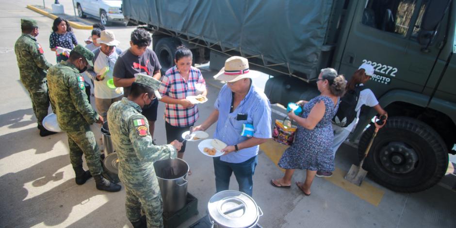Elementos del Ejército entregan platos de guisados calientes para los afectados.
