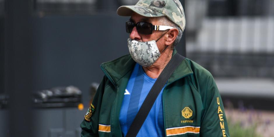 Una hombre camina por la calle, cubriendo sus vía respiratorias con un cubrebocas