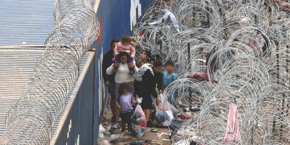 Una familia de migrantes mexicanos busca librar los alambres de púas para entrar a Eagle Pass.