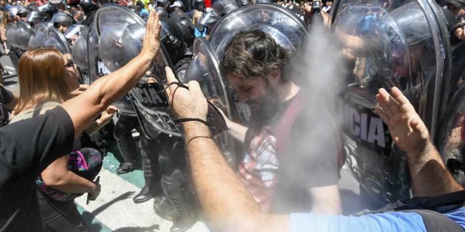 Manifestantes chocan con agentes que los rocían con gas, ayer.