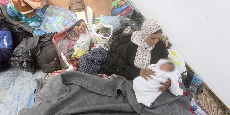Una mujer palestina desplazada sostiene a su bebé en una tienda de campaña cerca del cruce de Kerem Shalom en Rafah el pasado 14 de enero.