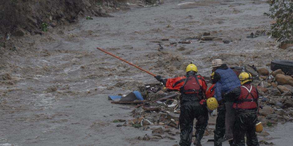 Rescatistas ayudan a un hombre de la tercera edad a salir de un arroyo en el que quedó atrapado, ayer.