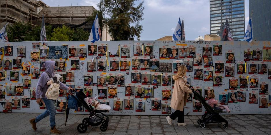 Varias personas caminan frente a un muro con fotografías de rehenes, secuestrados por Hamás en sus ataques contra Israel, ocurridos el 7 de octubre de 2022, en Tel Aviv, Israel.