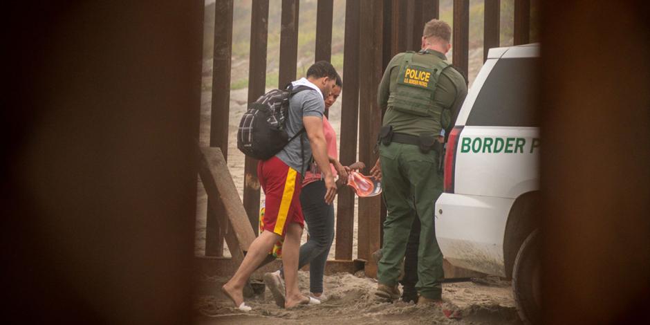 Pareja migrante cruza el muro fronterizo de Playas de Tijuana