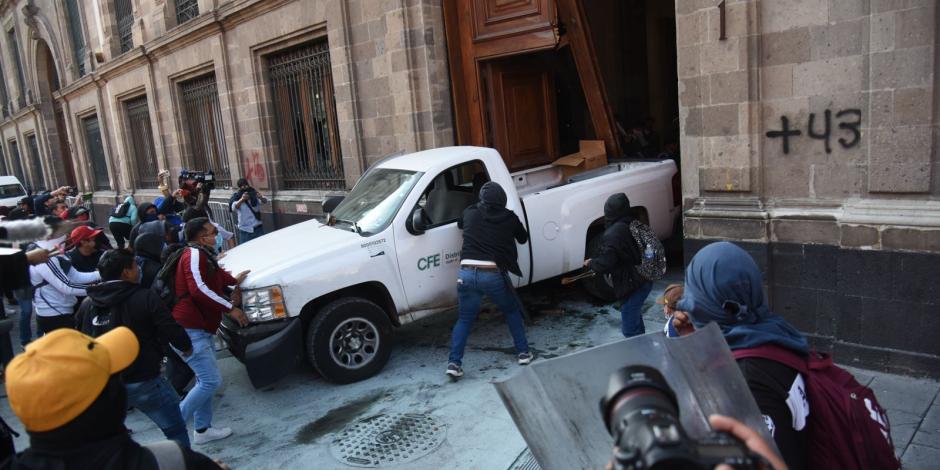Manifestantes usan como ariete camioneta de la CFE para vulnerar puerta de Palacio.