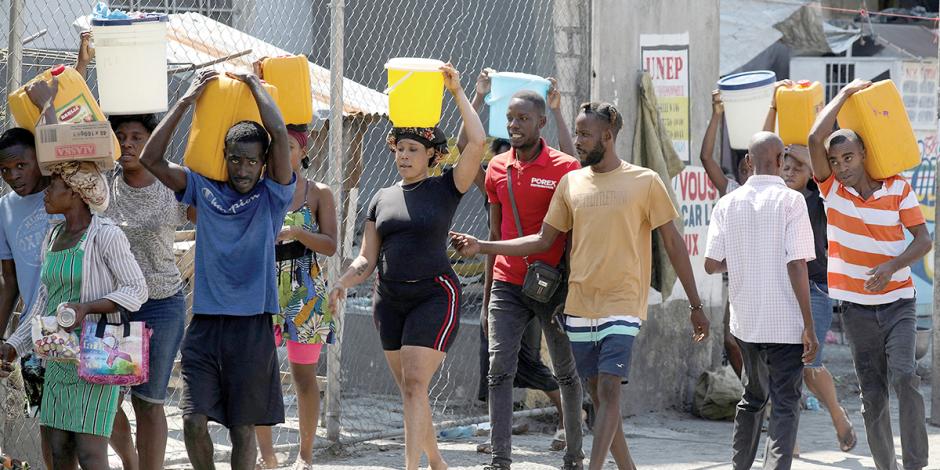 Habitantes de Puerto Príncipe cargan agua en cubetas y contenedores, el pasado 12 de marzo.