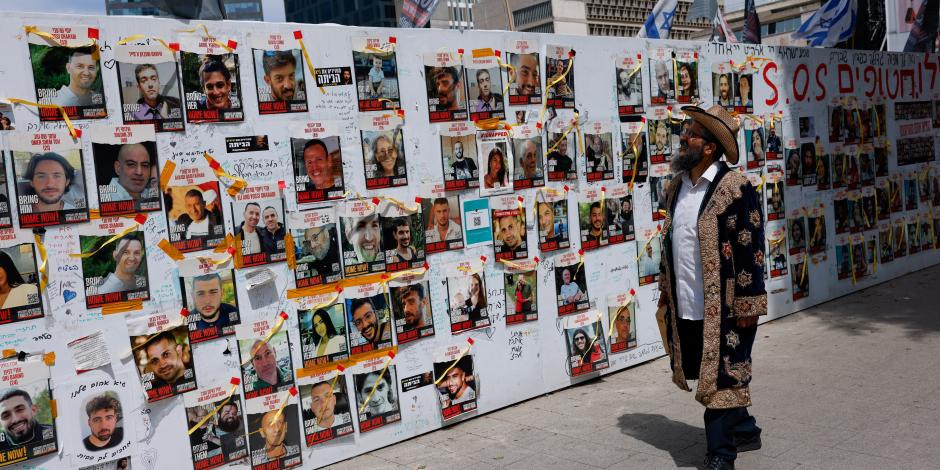 Un ciudadano lee los carteles pegados en un muro con los rostros de los rehenes, ayer.