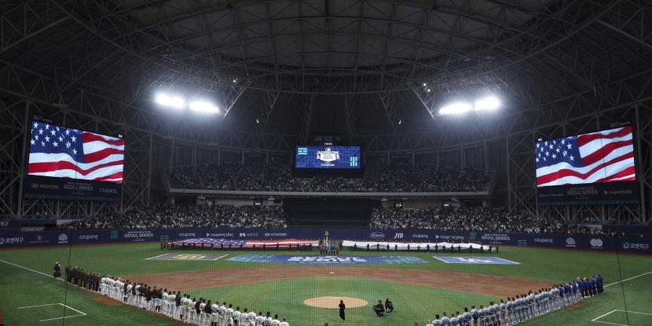 Miembros de los Dodgers y los Padres escuchan el himno nacional antes del partido del día inaugural en Corea del Sur.