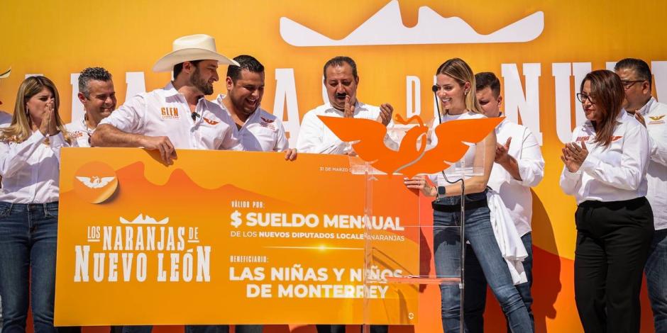 Mariana Rodríguez Cantú recibe un cheque simbólico de candidatos de MC comprometidos con donar sus salarios al DIF Capullos.