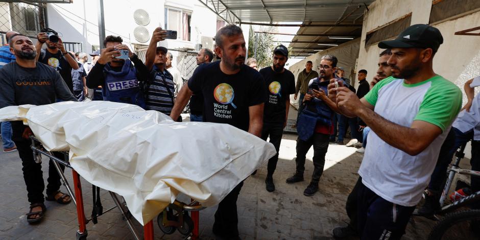 Personas llevan el cuerpo de uno de los trabajadores extranjeros asesinados, ayer en Rafah, Gaza.