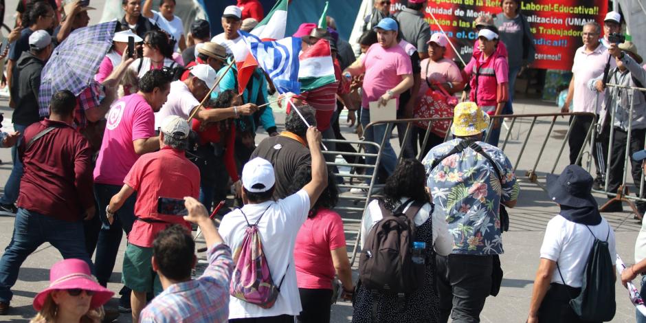 Miembros de la Marea Rosa retiran una valla del campamento de la CNTE, ayer.