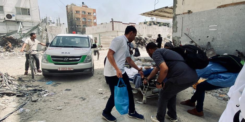 Voluntarios ayudan a evacuar a víctimas en un hospital en Gaza, ayer.