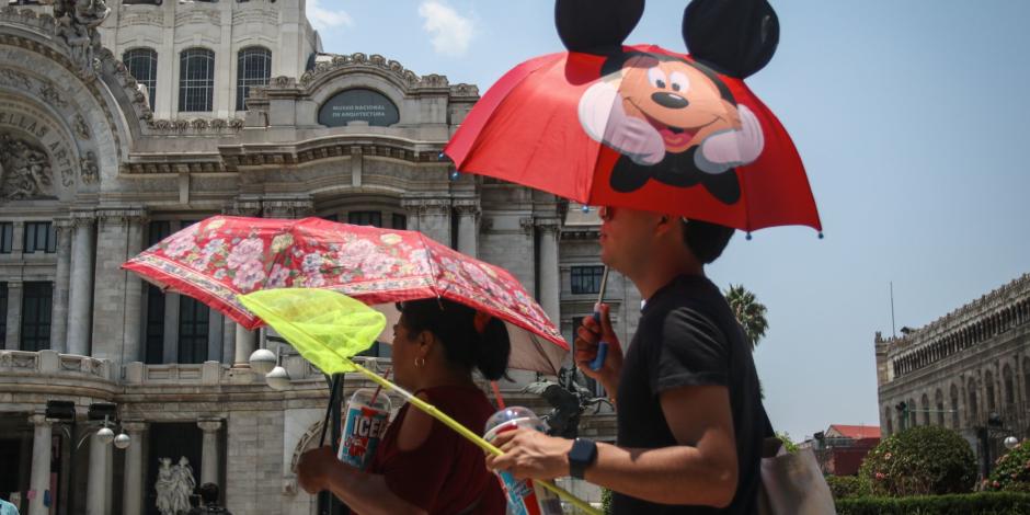 Personas se protegen del sol con sombrillas, ayer en la Ciudad de México.