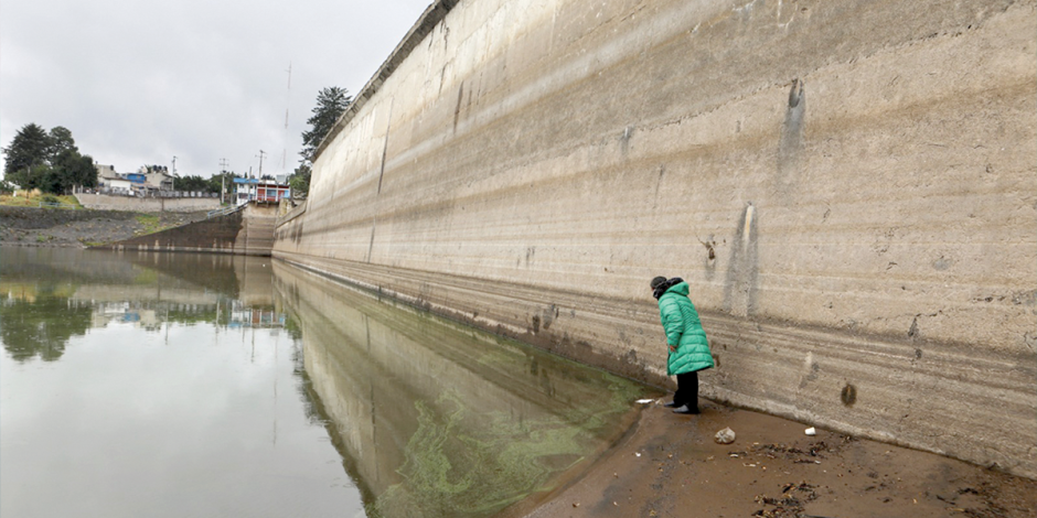 Una Mujer revisa el lecho parcialmente seco de la presa  de Villa Victoria.