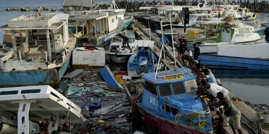 Residentes de Santa Lucía intentan desatascar un barco en un puerto de Barbados, ayer.