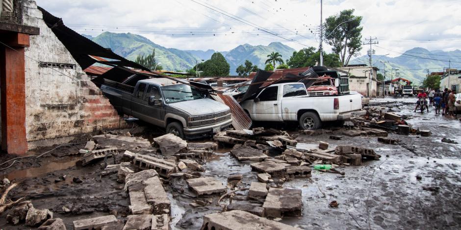 Camionetas incrustadas en viviendas convertidas en escombros lucen en calles de Venezuela.