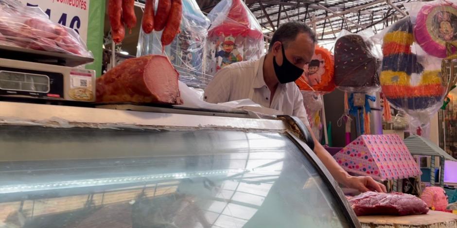 Un hombre trabaja un corte de carne dentro de un mercado público de la Ciudad de México.