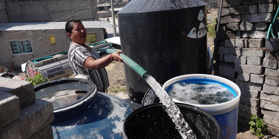Una mujer llena con agua sus tambos y tinacos con la manguera de una pipa del Gobierno, en febrero pasado.