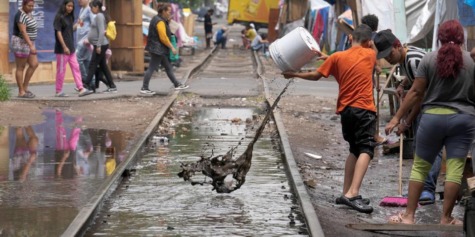 Migrantes en un campamento de la colonia Vallejo sacan el agua acumulada por las fuertes lluvias de los últimos días, el pasado jueves 18 de julio.