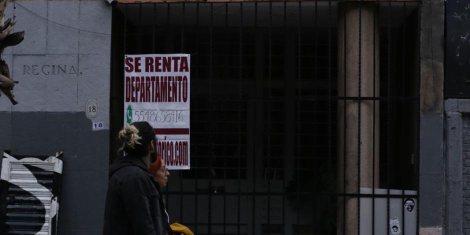 Dos jóvenes caminan frente un inmueble con un apartamento en renta.