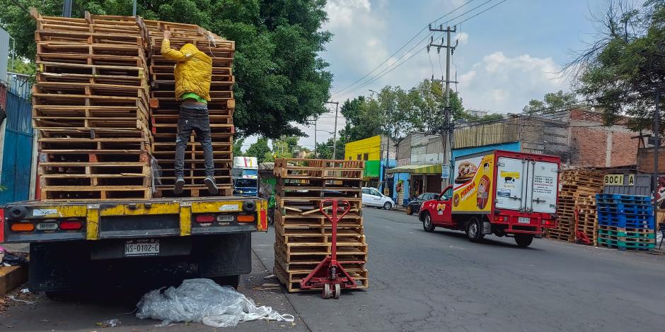 Un trabajador carga tarimas a una camioneta en un sitio no autorizado, el martes.
