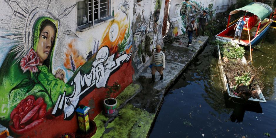 Chinamperos llevan a cabo la limpieza d eun canal de Xochimilco a un costado de varias viviendas, en 2020.