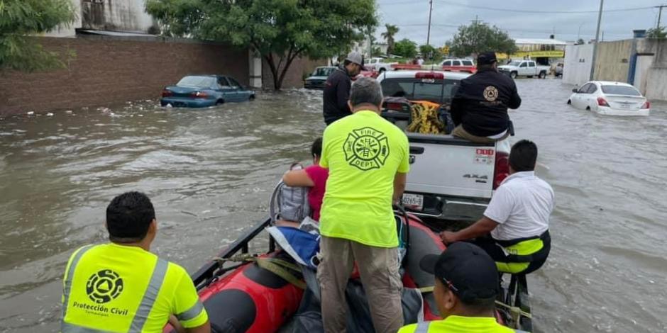 Elementos de Protección Civil del Gobierno de Tamaulipas sacan a una familia de la zona afectada, ayer.