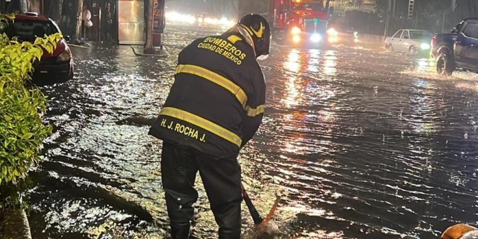 Bombero intenta destapar una coladera en Tlalpan para solucionar un encharcamiento, ayer.