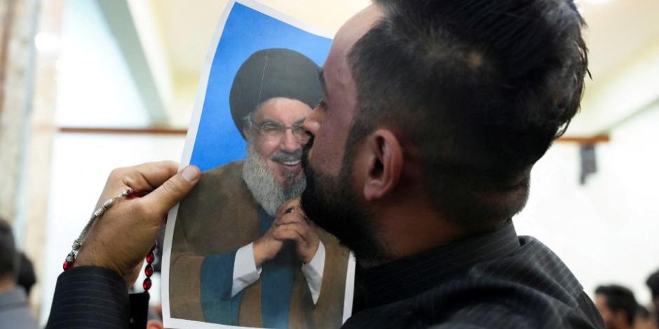 Un voluntario iraquí besa a foto del líder de Hezbolá Sayed Hasán Nasralá.