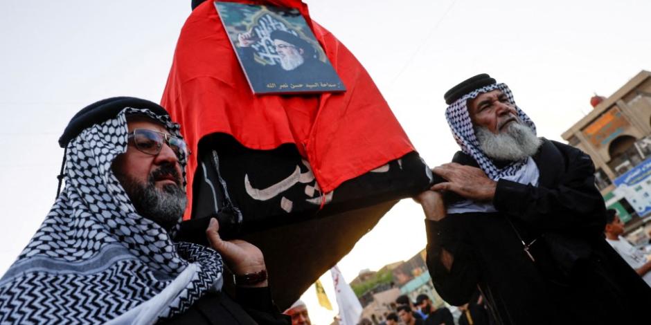 Manifestantes cargan un pequeño monumento a Hassan Nasrallah.