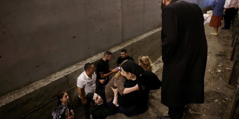 Ciudadanos se ayudan para ingresar a un refugio en el centro de Israel, mientras resuenan sirenas antiaéreas, ayer.