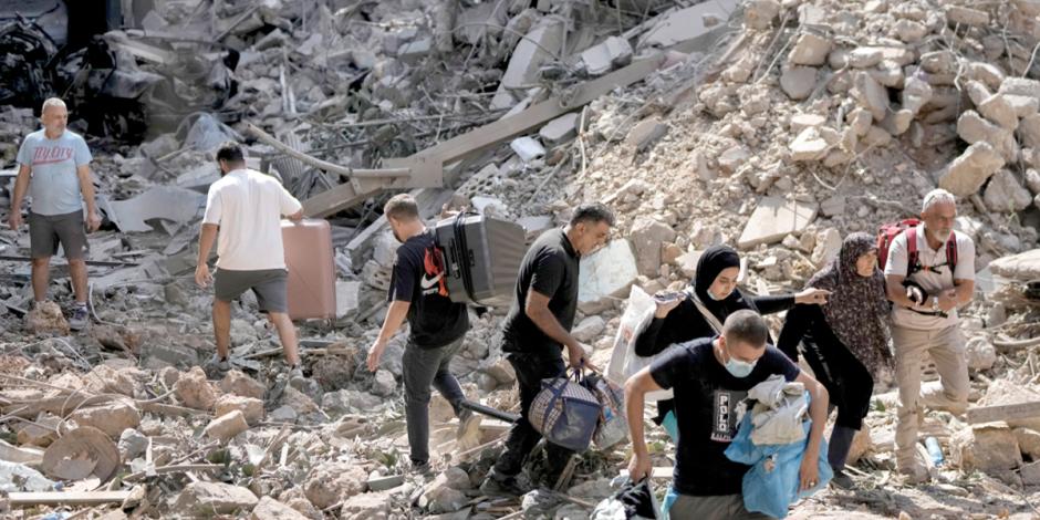 Residentes caminan sobre escombros tras un ataque a Beirut, ayer.