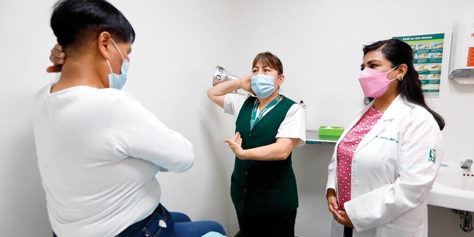 Una enfermera explica a una mujer cómo hacerse una revisión de seno para detectar tumores cancerígenos.