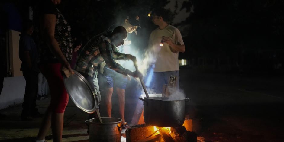 Pobladores cocinan en la calle en la oscuridad, guiados por una fogata, ayer.