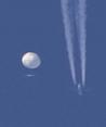 Un gran globo se desplaza por encima de la zona de Kingstown, Carolina del Norte, mientras por debajo se observa un avión y la estela que deja a su paso