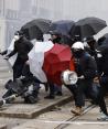 Armados con paraguas disidentes franceses se protegen del gas lacrimógeno, en París, ayer.